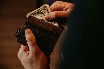 man pulling cash out of wallet; photo by Allef Vinicius on Unsplash