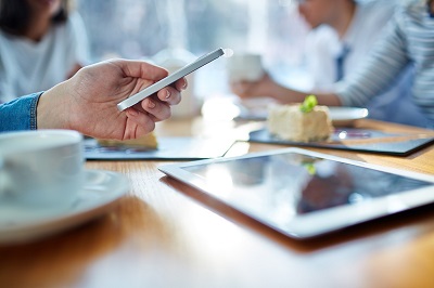 person looking at smartphone with tablet
