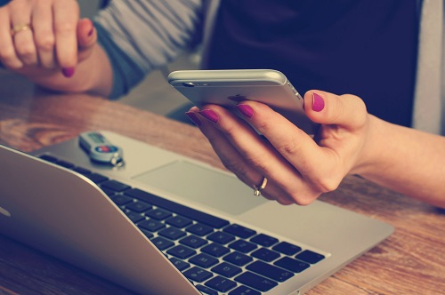 woman at laptop with smartphone
